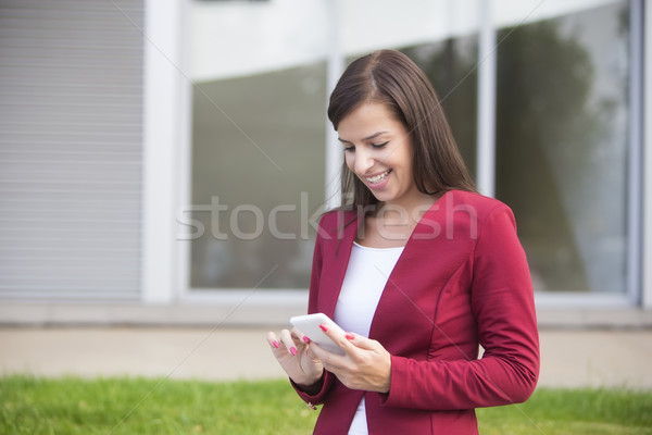 Fiatal üzletasszony piros blézer mobiltelefon szabadtér Stock fotó © boggy