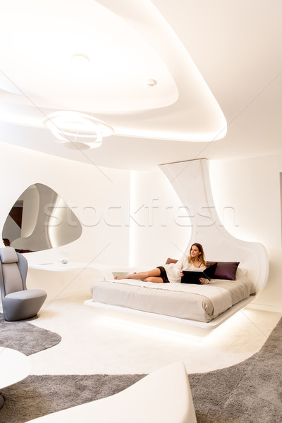Fiatal nő olvas katalógus ágy fehér hálószoba Stock fotó © boggy