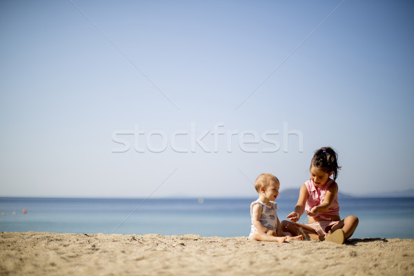 Cute little sisters sitting on a beach Stock photo © boggy