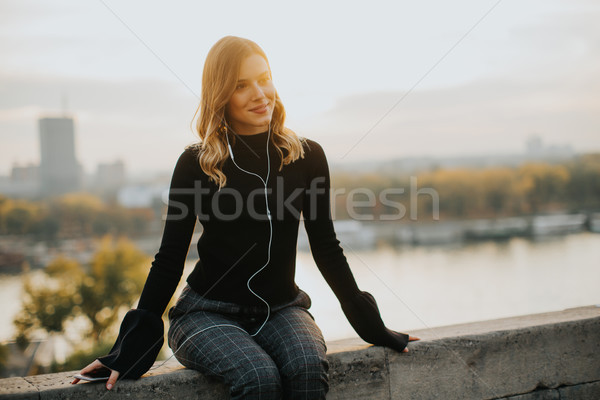 Trendy young woman listening music from smartphone outdoor at su Stock photo © boggy