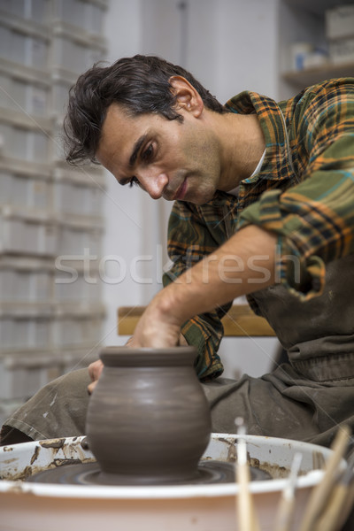 Artist makes clay pottery on a spin wheel in workshop Stock photo © boggy