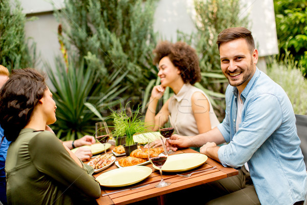 Friends grilling food and enjoying barbecue party outdoors Stock photo © boggy