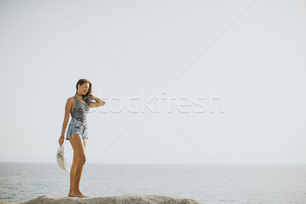 Pretty young woman on the stony shore Stock photo © boggy
