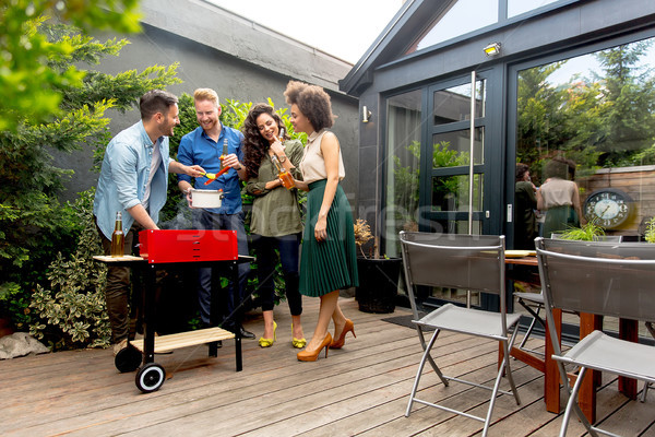 Friends grilling food and enjoying barbecue party outdoors Stock photo © boggy