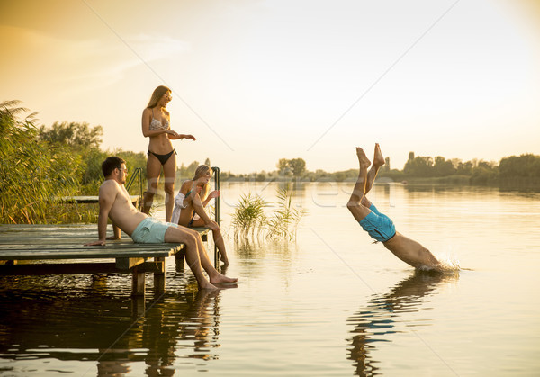 Group of young people having fun on pier at the lake Stock photo © boggy