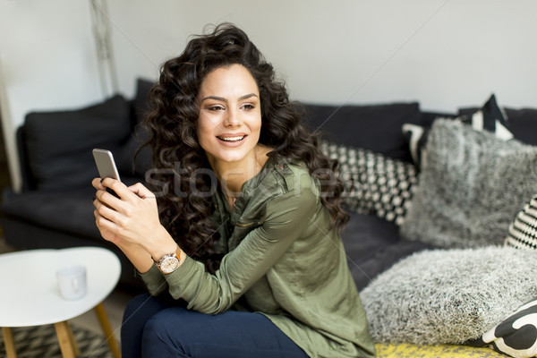 Mulher bonita cabelos cacheados sessão sofá quarto mulher jovem Foto stock © boggy