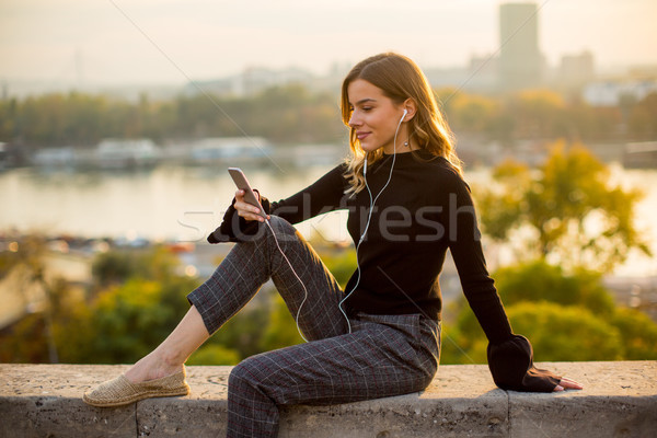 Trendy young woman listening music from smartphone outdoor Stock photo © boggy