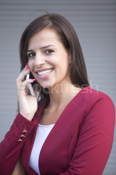 Young businesswoman in red blazer talking over the mobile phone Stock photo © boggy