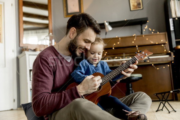 Father teaching daughter to play guitar at home Stock photo © boggy