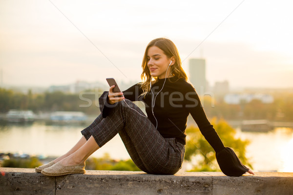 Stock photo: Trendy young woman listening music from smartphone outdoor at su