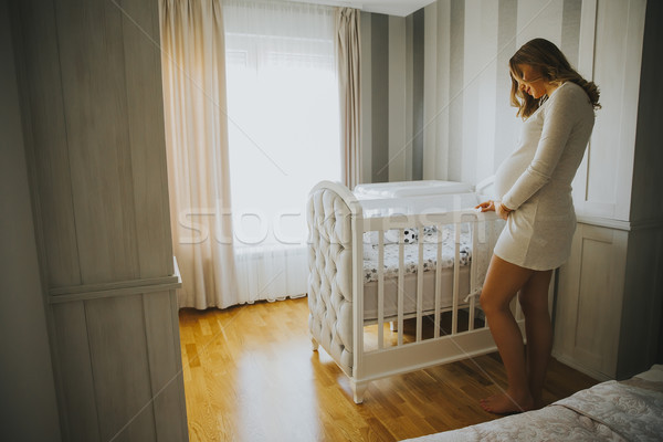 Pregnant woman setting up baby crib and smiling Stock photo © boggy