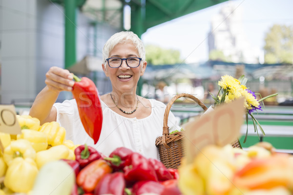 Good-looking senior woman wearing glasses buys pepper on market Stock photo © boggy