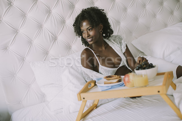 Smiling african american woman having a relaxing breakfast in be Stock photo © boggy