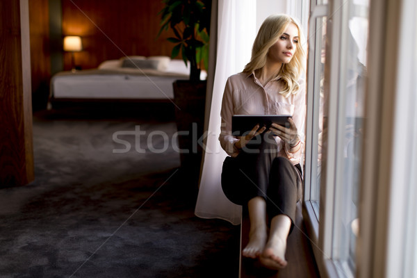 Stock photo: View at young businesswoman sitting by the window and using digi