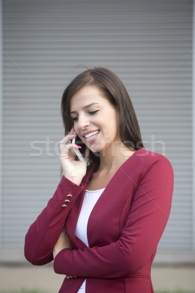 Young businesswoman in red blazer talking over the mobile phone Stock photo © boggy