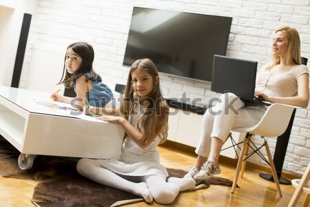 Stock photo: Woman using telephone at home while young girls drawing