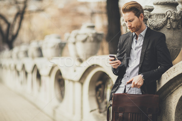 Young redhair businessman with mobile phone on a street Stock photo © boggy