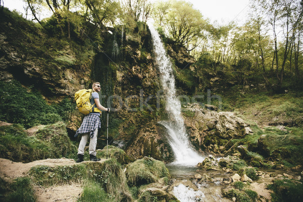 Young hiker stopped beside a mountain waterfall to rest Stock photo © boggy