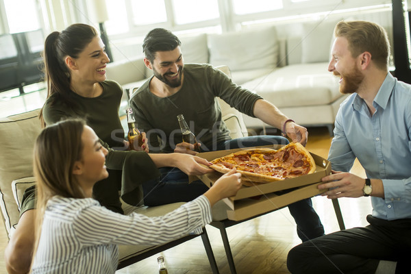 Young people eating pizza, drinking cider and have fun the room Stock photo © boggy
