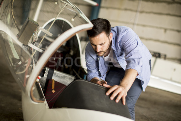 Young pilot checking airplane in the hangar Stock photo © boggy