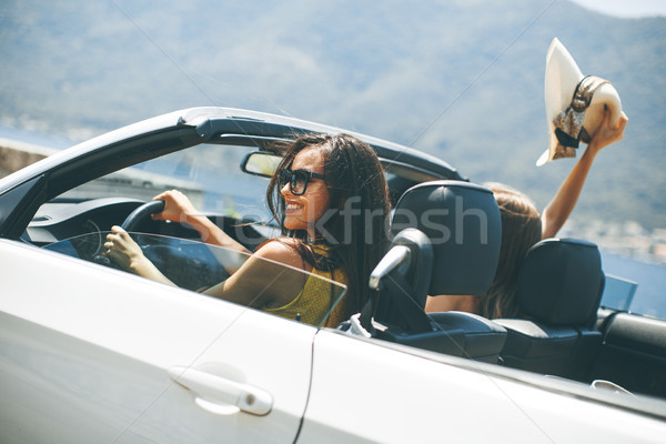 Young women in white cabriolet car driving everywhere and lookin Stock photo © boggy