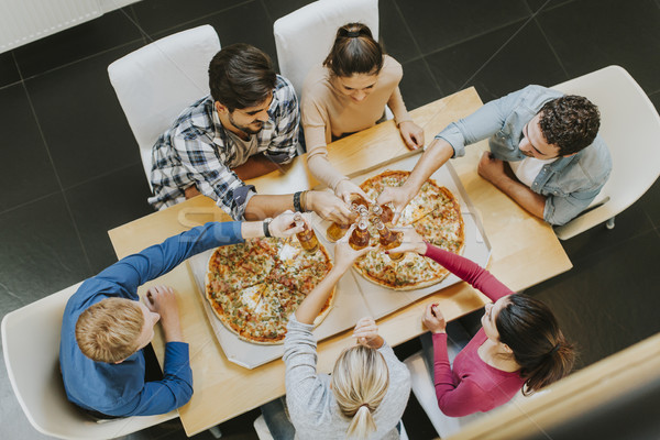 Group of young people eating pizza and drinking cider Stock photo © boggy