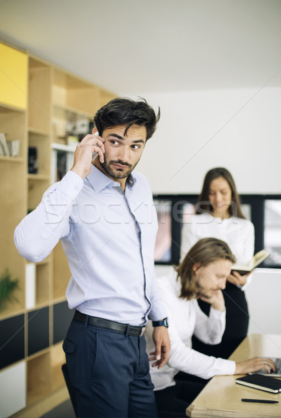 Handsome businessman using mobile phone in the office while othe Stock photo © boggy