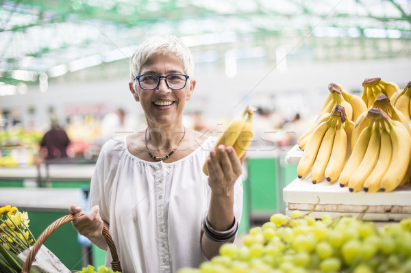 Good-looking senior woman buys bananas at the market Stock photo © boggy