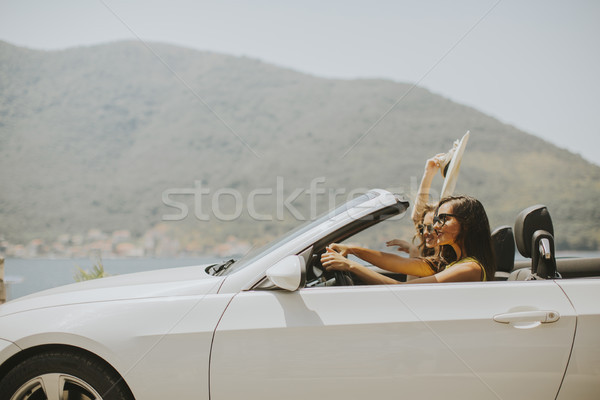 Two happy friends in white cabriolet car driving everywhere Stock photo © boggy