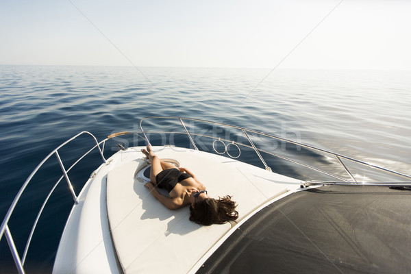 Young attractive woman lies and sunbathing on the bow of a luxur Stock photo © boggy