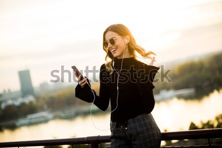 Stock photo: Trendy woman listening music from smartphone outdoor at sunset