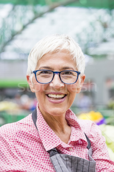 Good-looking senior woman wearing glasses sells  pepper on marke Stock photo © boggy