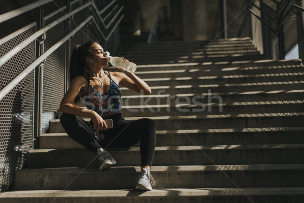 Stock photo: Young female runner resting on stairs