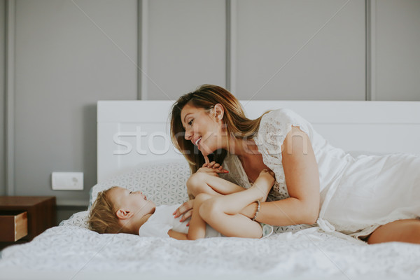 Mother playing with little boy on the bed in the room Stock photo © boggy