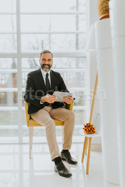 Middle age businessman with tablet in the office Stock photo © boggy