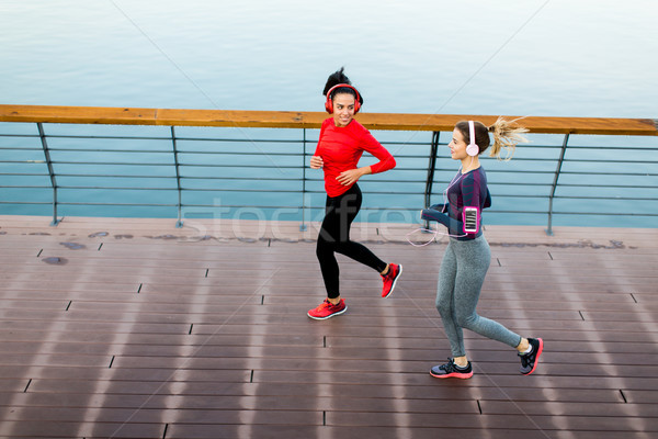 Two young women running on promenade by river Stock photo © boggy