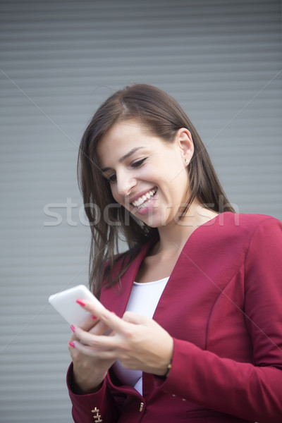 [[stock_photo]]: Jeunes · femme · d'affaires · rouge · blazer · téléphone · portable · extérieur