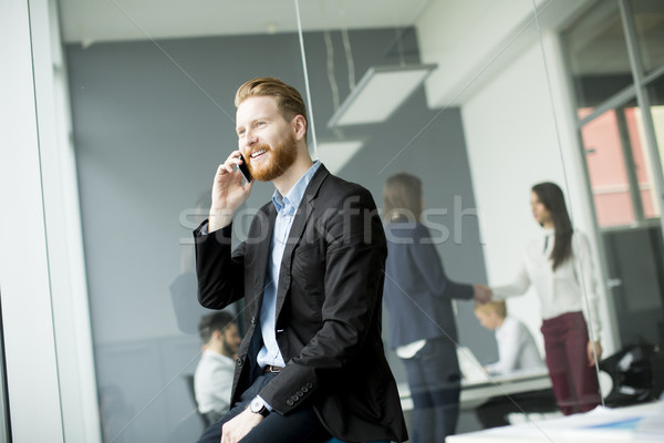 Businessman with ginger hair using mobile phone while other busi Stock photo © boggy