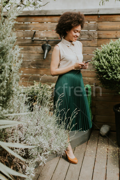 Curly hair young woman with a phone in his hand in the courtyard Stock photo © boggy