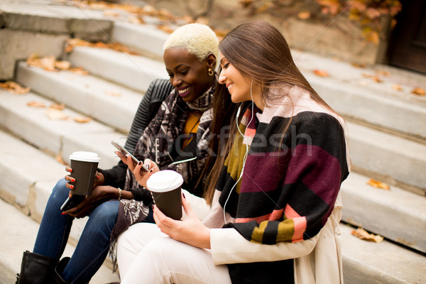 Multiracial friends sitting in autumn park, talking and carry co Stock photo © boggy