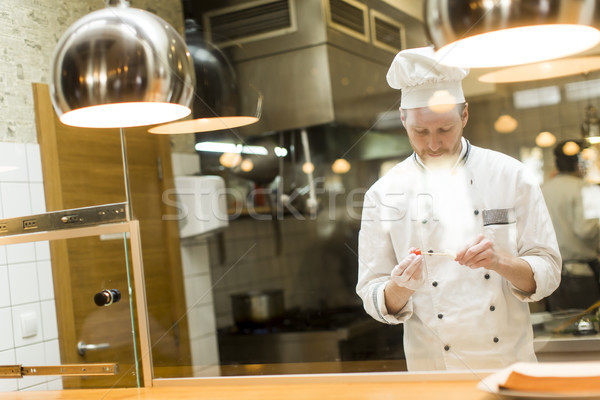 Young chef standing in a modern kitchen in the restaurant and pr Stock photo © boggy