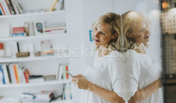 Confident blonde business woman standing and using phone in an o Stock photo © boggy