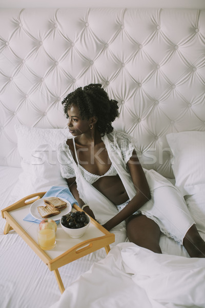 Smiling african american woman having a relaxing breakfast in be Stock photo © boggy