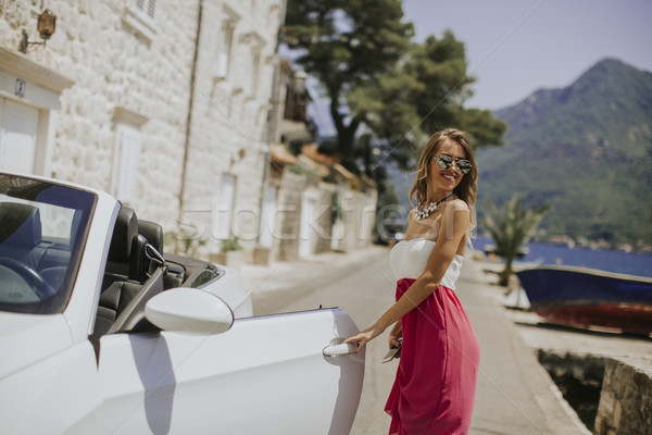 Pretty young woman by the white cabriolet car Stock photo © boggy