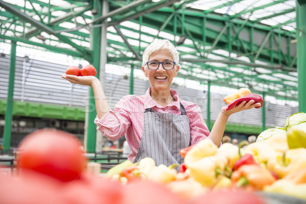 Good-looking senior woman wearing glasses sells  pepper on marke Stock photo © boggy