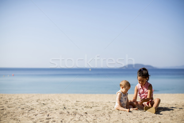 Cute little sisters sitting on a beach Stock photo © boggy