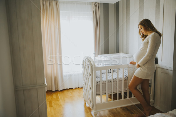 Pregnant woman setting up baby crib and smiling Stock photo © boggy
