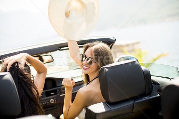 Young women in white cabriolet car driving everywhere and lookin Stock photo © boggy