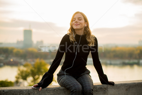 Trendy young woman listening music from smartphone outdoor at su Stock photo © boggy
