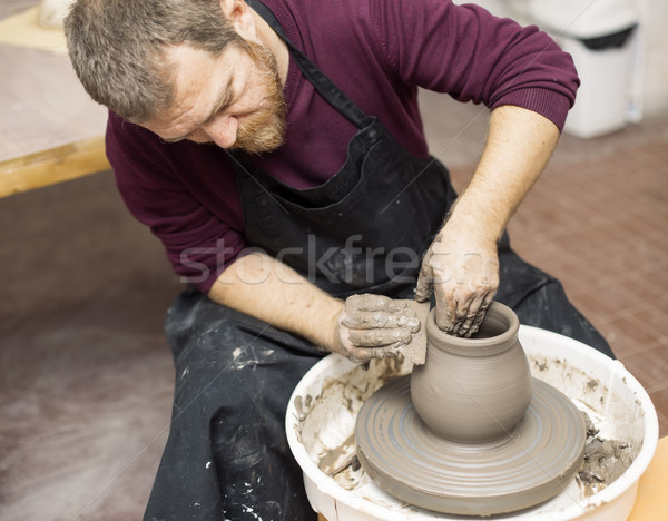 Male artist makes clay pottery on a spin wheel Stock photo © boggy